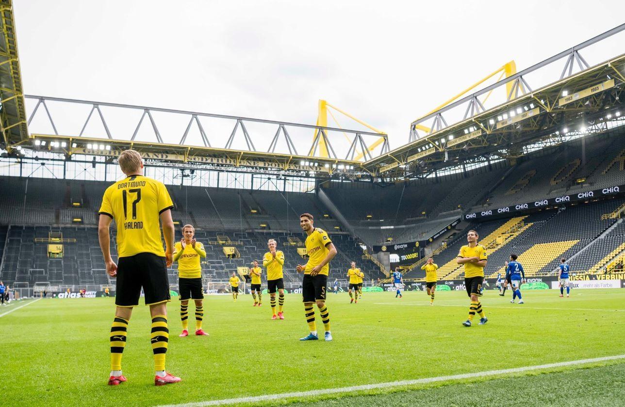 I calciatori del Borussia Dortmund festeggiano a distanza il gol dell'1-0 contro lo Schalke 04 