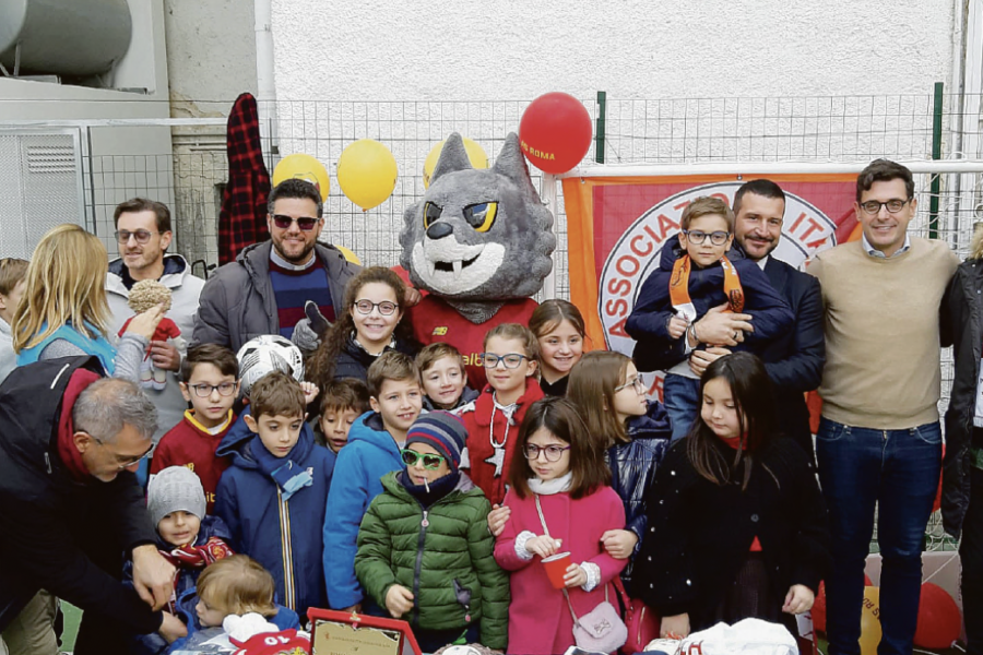 I componenti del Roma Club Trani nel campetto con tutti i bambini che hanno partecipato all’inaugurazione insieme al dirigente della Roma Francesco Pastorella, i rappresentanti dell’Airc e la mascotte Romolo 