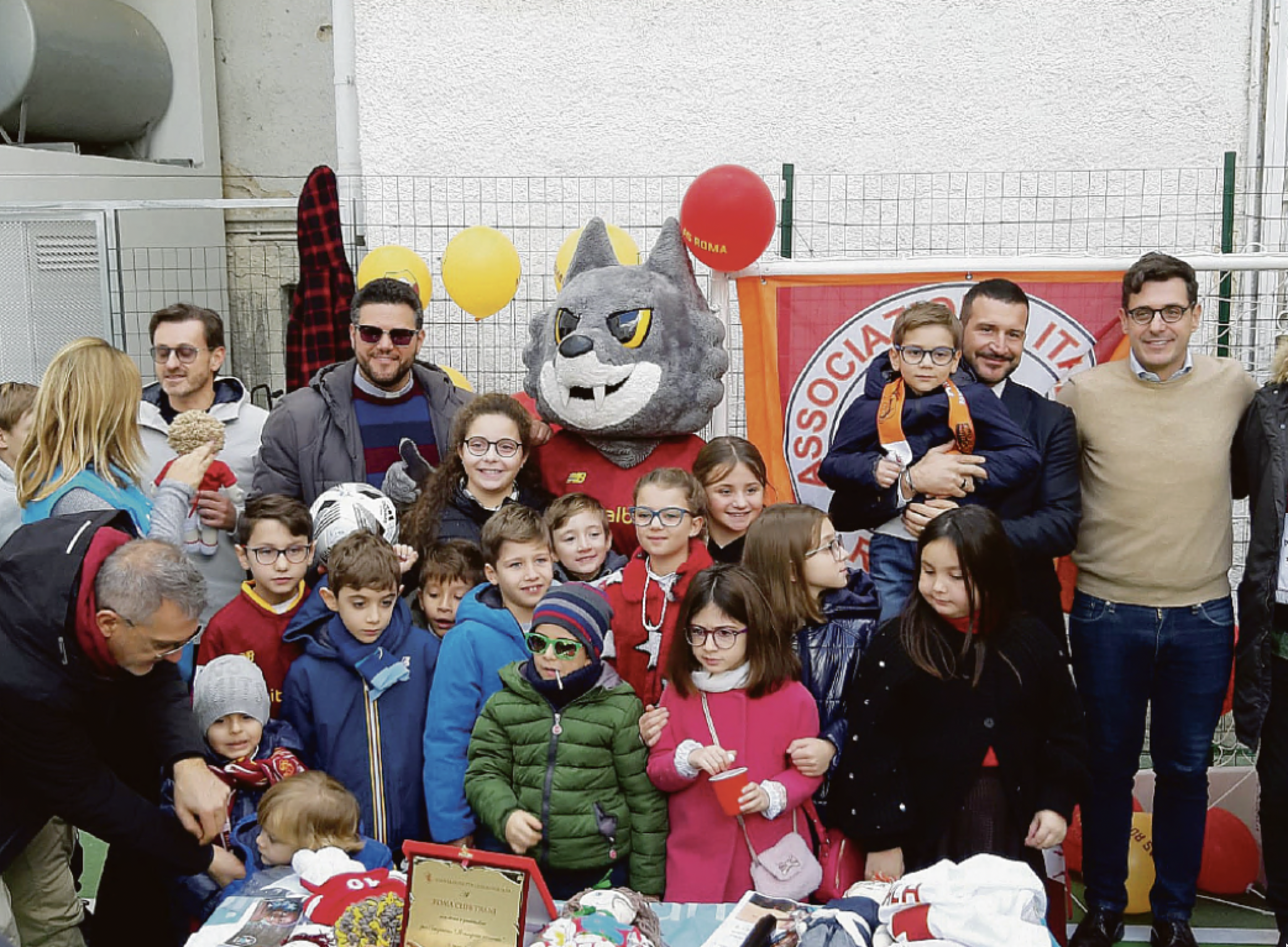 I componenti del Roma Club Trani nel campetto con tutti i bambini che hanno partecipato all’inaugurazione insieme al dirigente della Roma Francesco Pastorella, i rappresentanti dell’Airc e la mascotte Romolo 
